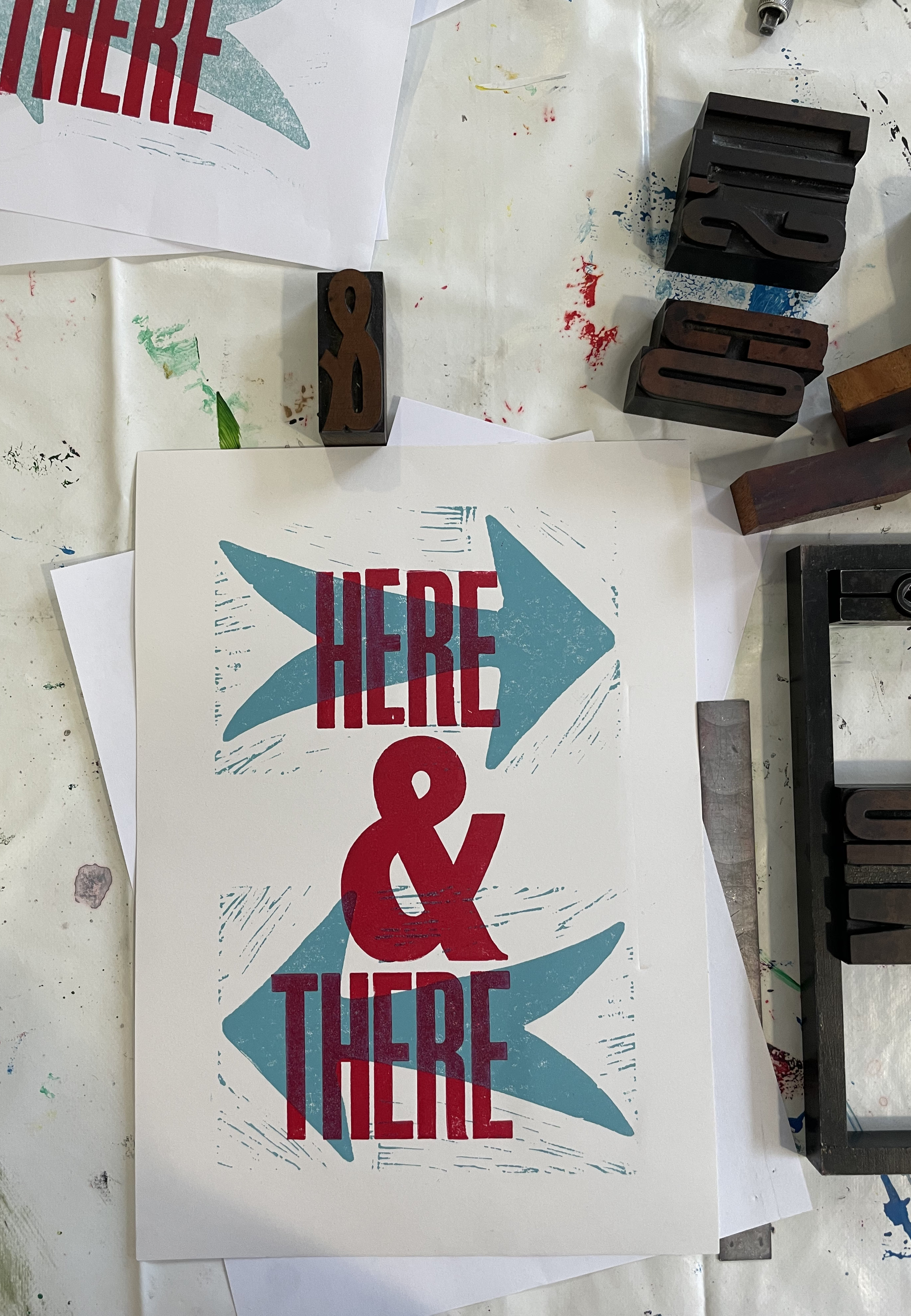 Letterpress print, 'Here and there' is written in text on top of two lino prints of arrows