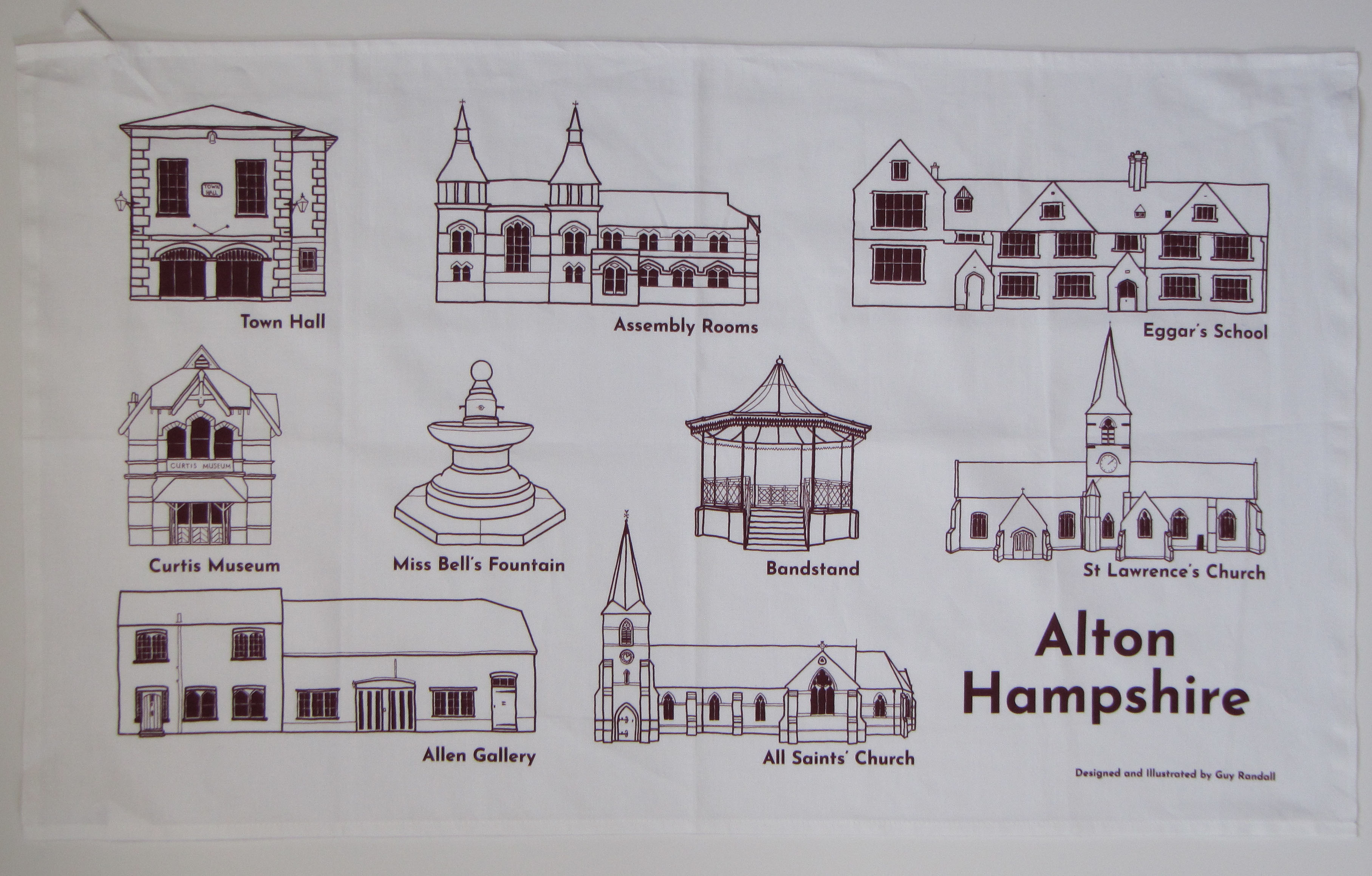 Photograph of the printed tea towel with line drawings of various buildings in Burgundy